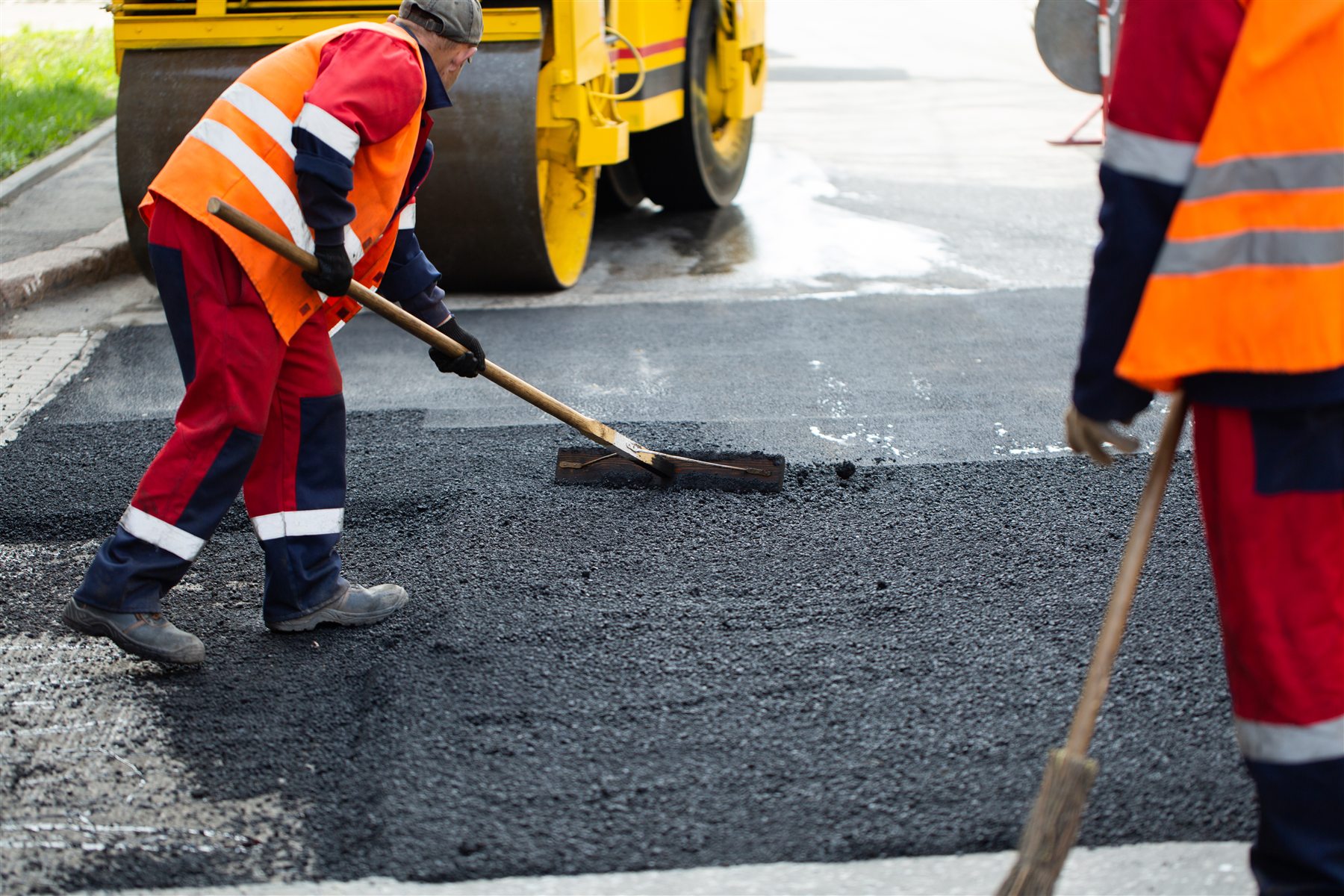 Road workers hand-finishing fresh asphalt