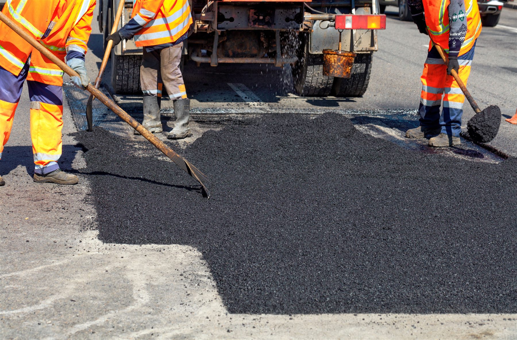 Road crew placing fresh asphalt patch material